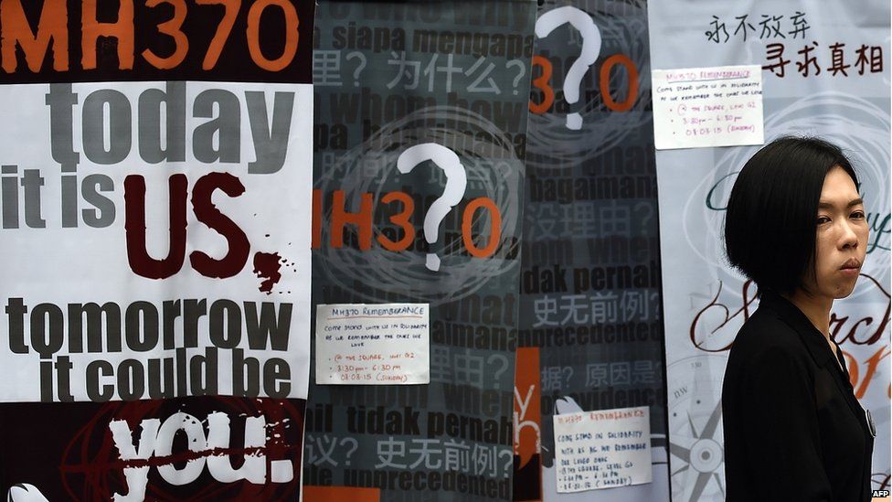 A woman walks past placards highlighting the missing Malaysia Airlines flight MH370, during a remembrance event in Kuala Lumpur on 8 March 2015