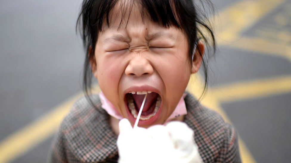 A girl reacts to the throat swab in the mandatory all-inclusive Covid-19 test in Wuhan in central China's Hubei province Sunday, March 06, 2022