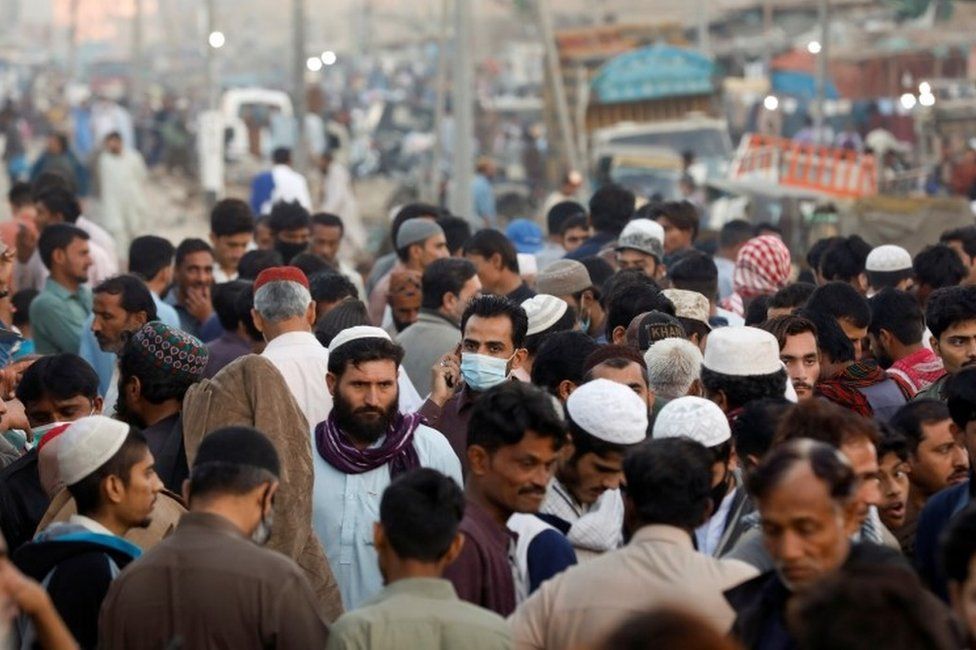 Мужчина в защитной маске идет сквозь толпу людей по импровизированному рынку, в то время как вспышка коронавирусной болезни (COVID-19) продолжается в Карачи, Пакистан, 17 января 2021 года.