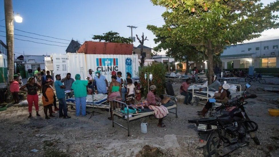 Patients accompanied by their relatives are seen outside a hospital damaged following a 7.2 magnitude earthquake in Les Cayes,