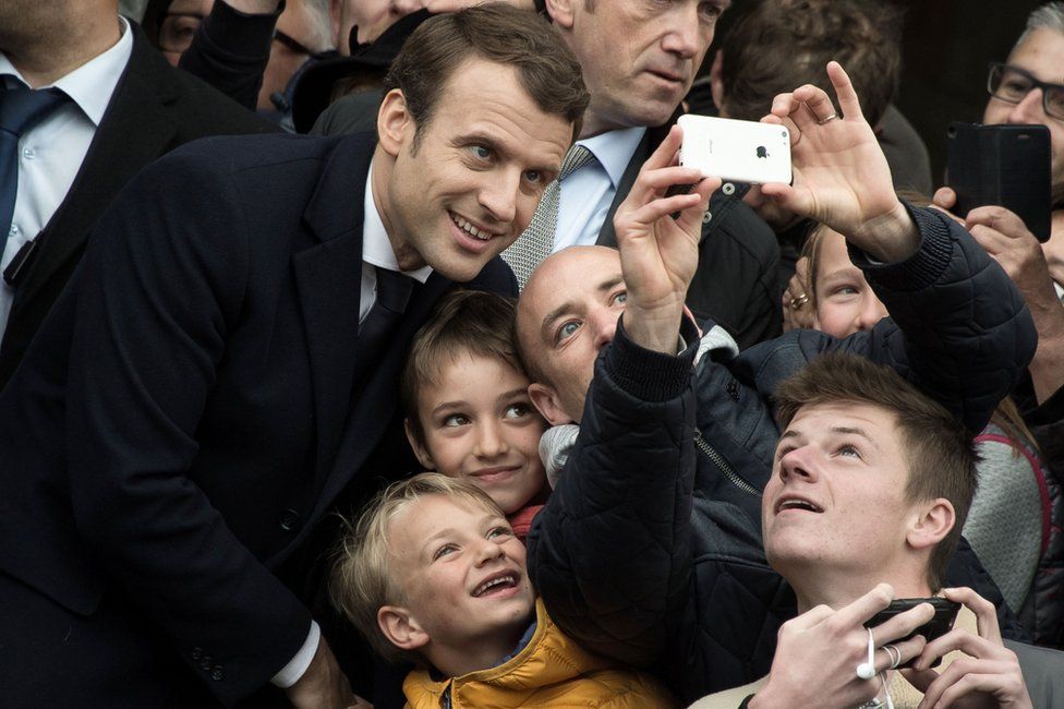 Supporters take photographs with the French President Emmanuel Macron