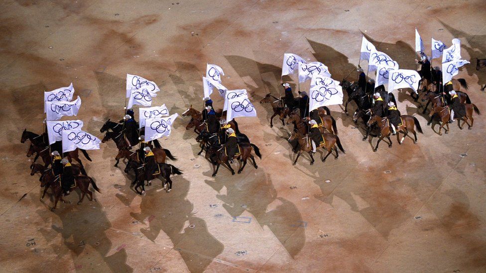 Horseriders carry Olympic flags during the opening ceremony of the Sydney 2000 Olympic Games, September 15, 2000 in the Olympic Stadium in Sydney
