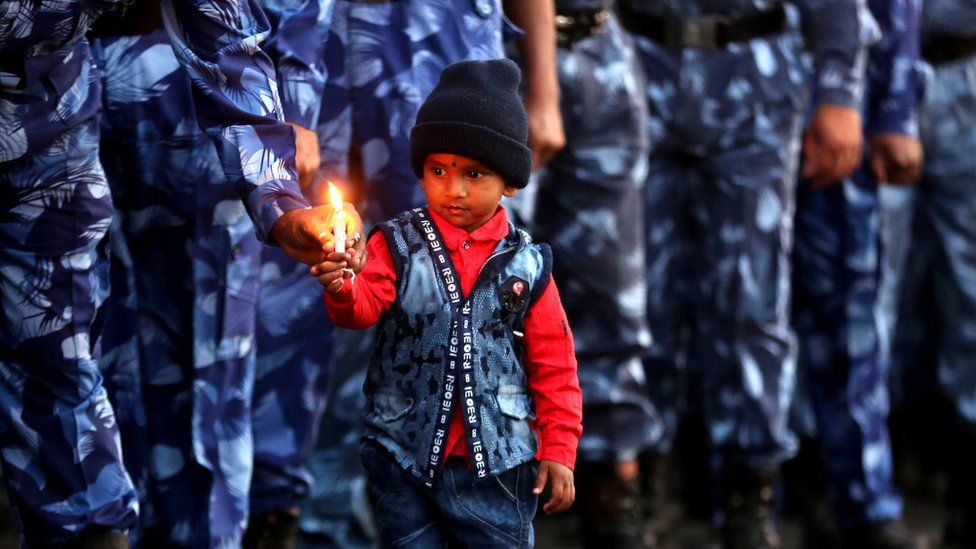 Rapid Action Force soldiers and a child from one of their families hold candles as they pay tribute to personnel during a candlelight vigil in Bhopal