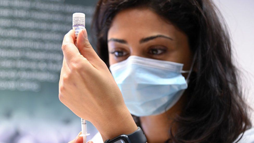 A pharmacist prepares to give a COVID-19 booster vaccination