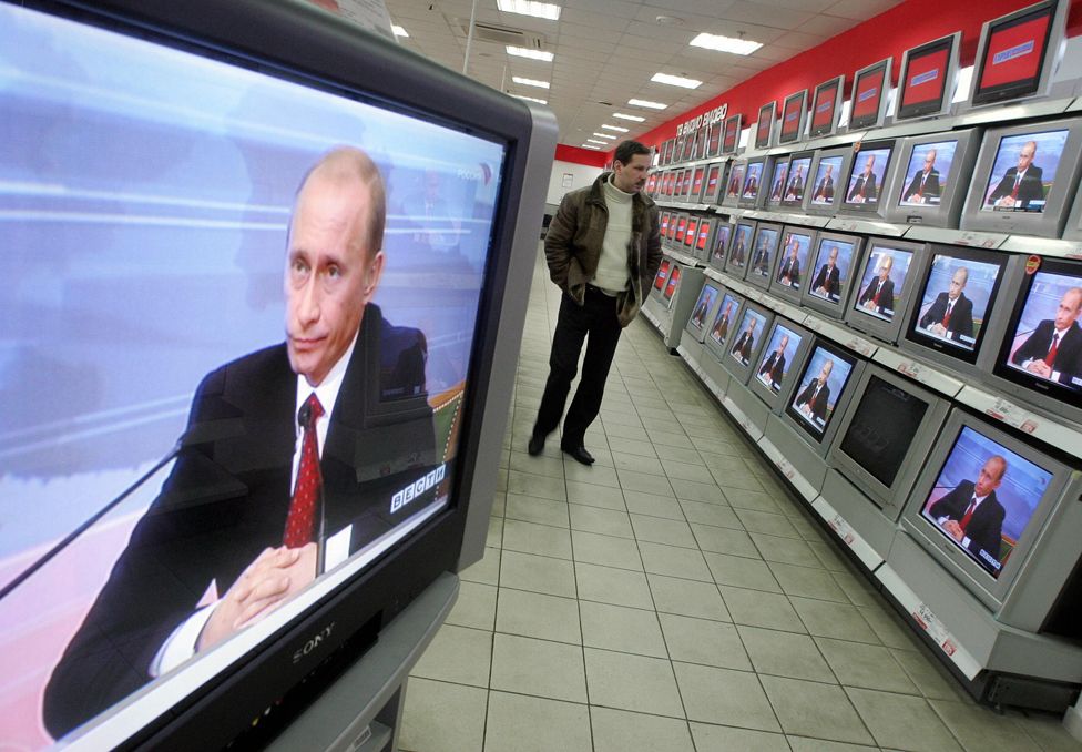 A man looks at TV sets, broadcasting live the annual press conference of the Russian President Vladimir Putin in an electronics store in Moscow. 31 January 2006.