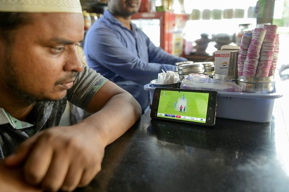 An Indian fan watches a live broadcast of the Cricket World Cup match between India and Pakistan on a mobile phone at a paan shop (food preparation composed of betel leaf and areca nut) in Hyderabad on June 16, 2019.