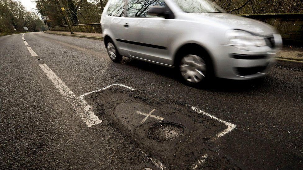A car driving past a pothole