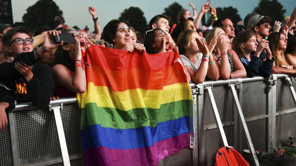 Festival goers enjoying seeing an act play at Latitude Festival in Suffolk, one person is holding up a flag