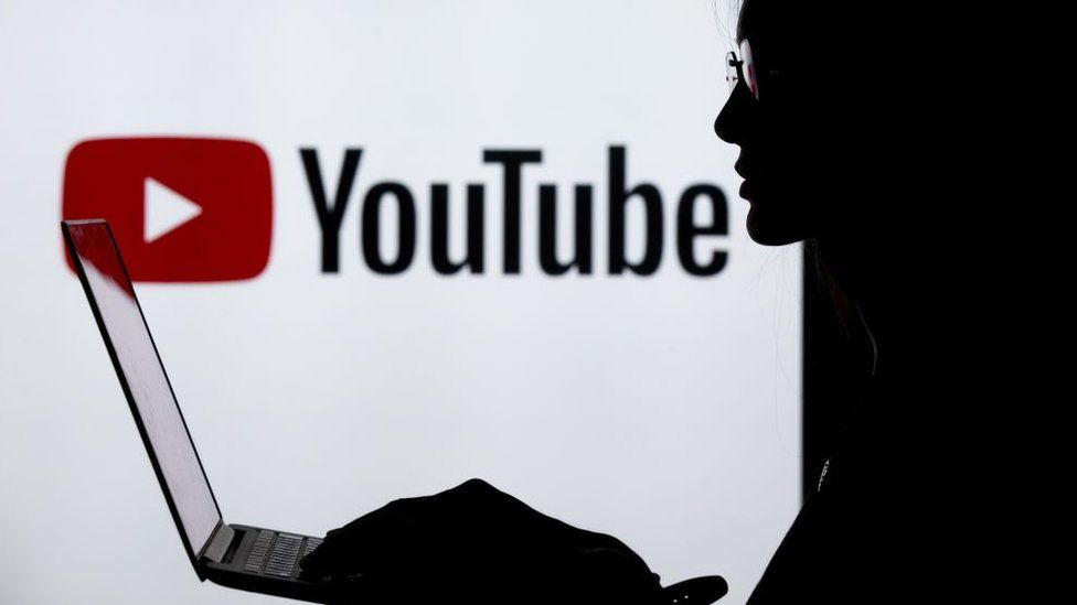 A silhouette of a woman in front of the YouTube logo