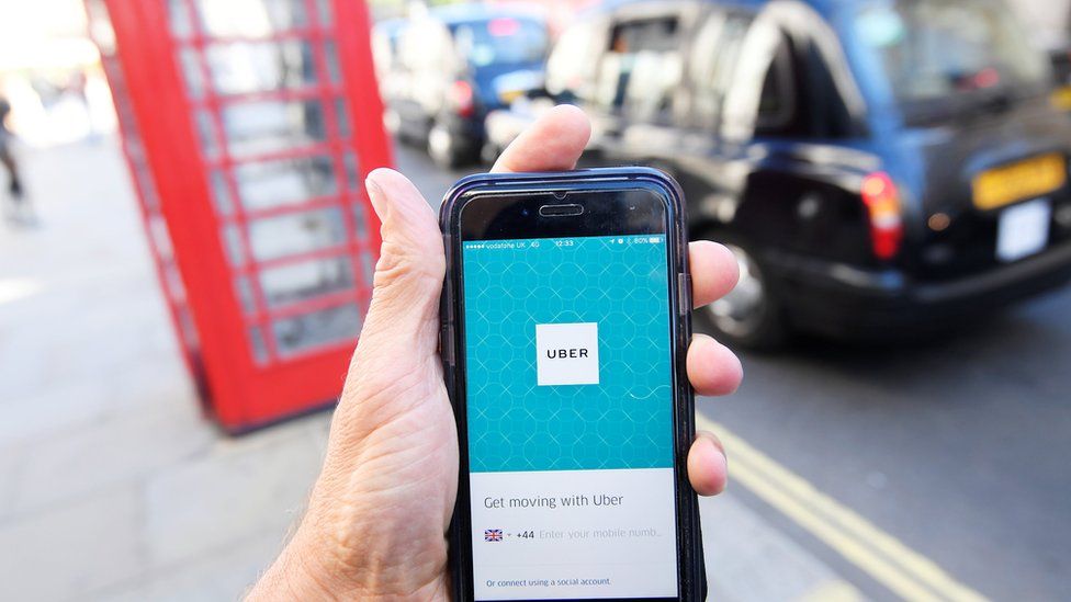 Uber phone app with a phone box and black cab in the background