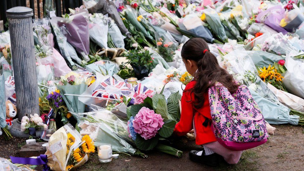 A girl leaves flowers at Windsor Castle on Friday, following the death of Queen Elizabeth II