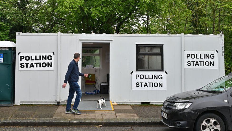 A man walks his dog past a portable polling booth on May 02, 2024 in Leigh on Sea, England