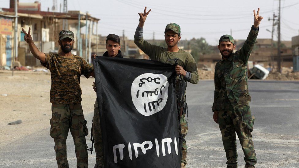 Iraqi members of the Hashed al-Shaabi (Popular Mobilisation units) carry an upsidedown Islamic State (IS) group flag in the city of al-Qaim, in Iraq"s western Anbar province near the Syrian border as they fight against remnant pockets of Islamic State group jihadists on November 3, 2017.