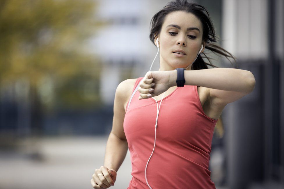 Woman jogging and looking at fitness band