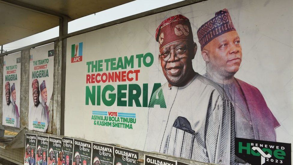 APC campaign posters showing Bola Ahmed Tinubu and running mate Kashim Shettima at a bus stop in Lagos.