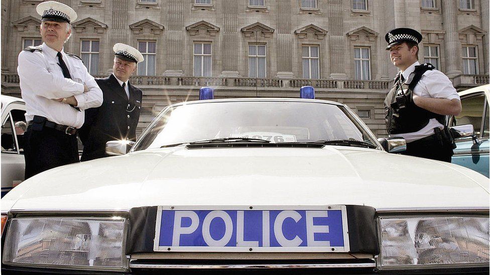 LONDON, UNITED KINGDOM: British Police officers stand 22 April 2006 beside a 1976 Rover SD1 3500 Police car, one of 80 historic British-built motor vehicles, outside Buckingham Palace in London. The classic motors were exhibited in honour of the Queen Elizabeth II's birthday, which she celebrated 21 April with a walkabout in Windsor which attracted crowds of 20,000 people and a private dinner at Kew Palace with her family which featured a spectacular fireworks display. AFP PHOTO POOL PA - A