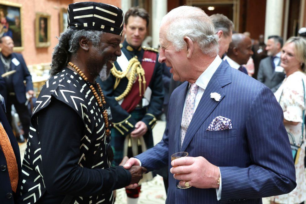 King Charles shakes hands with a guest during a reception to mark the 75th anniversary of Windrush at Buckingham Palace on 14 June, 2023