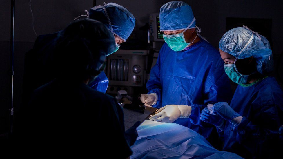 Generic surgical team in blue scrubs performing operation on patient in hospital