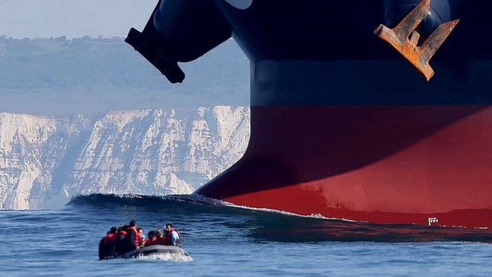 Migrants on a dinghy crossing the English Channel from France to the UK narrowly avoid colliding with an oil tanker