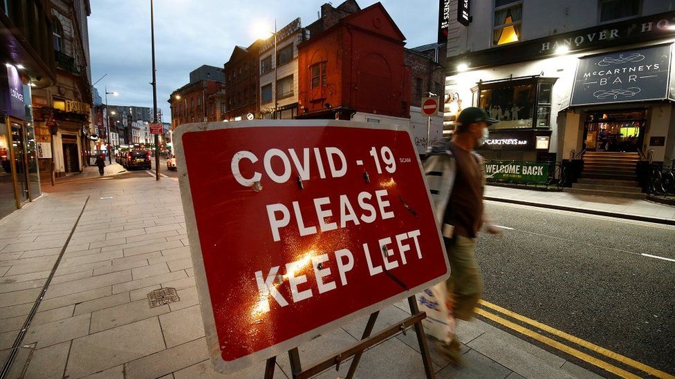 A man walks past a social distancing sign in Liverpool City Centre