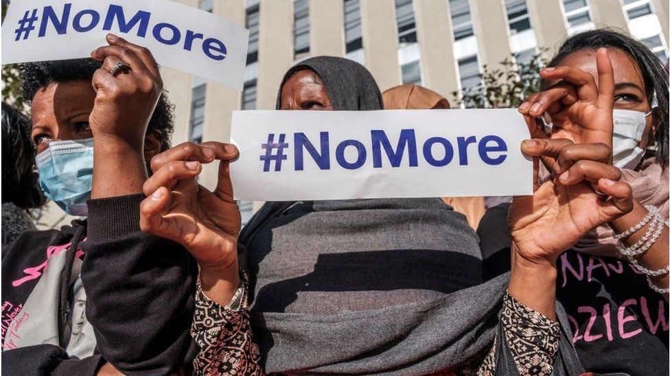 Women at a protest with signs that say #NoMore