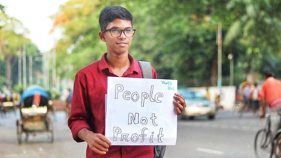 16-year-old Bangladeshi student Yudhishtir Chandra Biswas holds up a sign saying "people not profit"