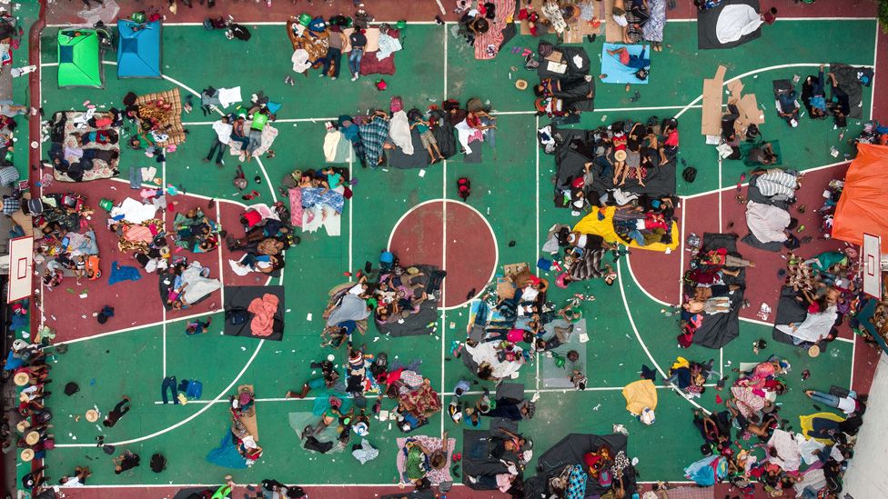 Migrants sleep on a basketball court