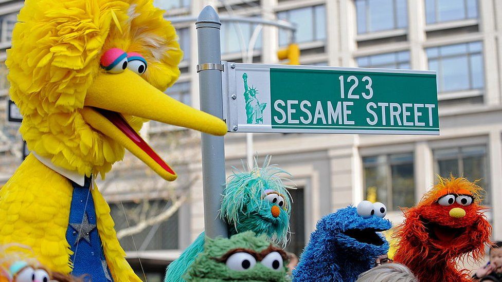 Big Bird (L) and other Sesame Street puppet characters pose next to temporary street sign November 9, 2009