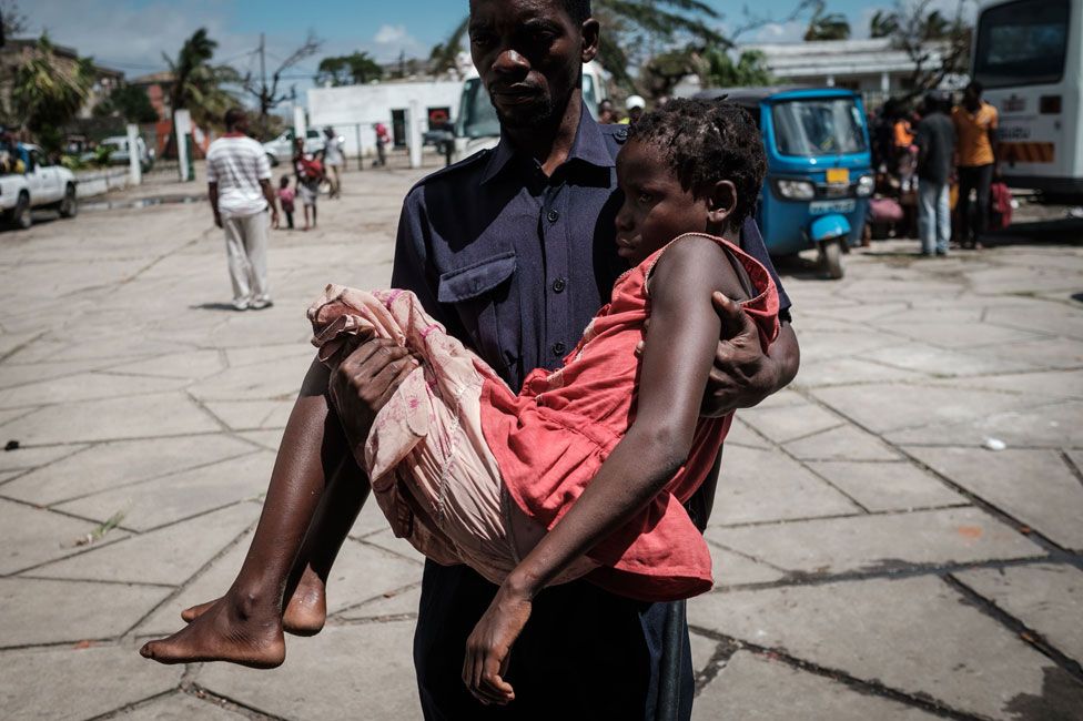 A girl who was evacuated by boat from the isolated district of Buzi is carried by a Red Cross staff on her arrival at Samora M. Machel secondary school turned evacuation center in Beira, Mozambique, on March 21, 2019.