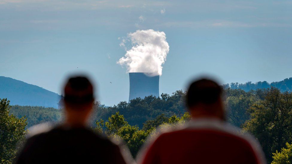 Two men stand facing the cooling tower of the nuclear power plant of Goesgen from the city of Aarau, Switzerland