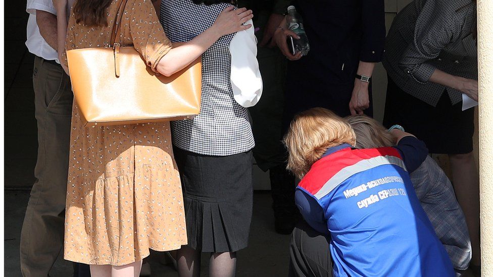 A medical worker comforts relatives of students of School No 175 in Kazan, 11 May