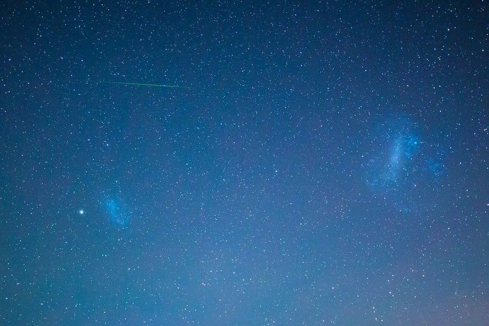 A meteor streaks past the Magellanic Clouds, two galaxies visible from the southern hemisphere