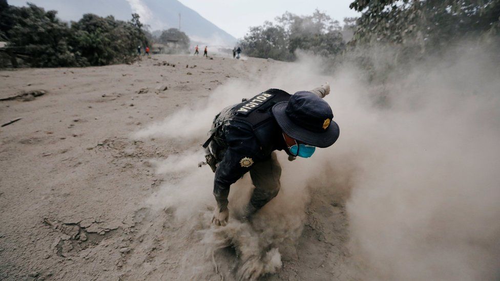 A police officer stumbles while running away after a the Fuego volcano spew new pyroclastic flow in the community of San Miguel Los Lotes in Escuintla, Guatemala, June 4, 2018
