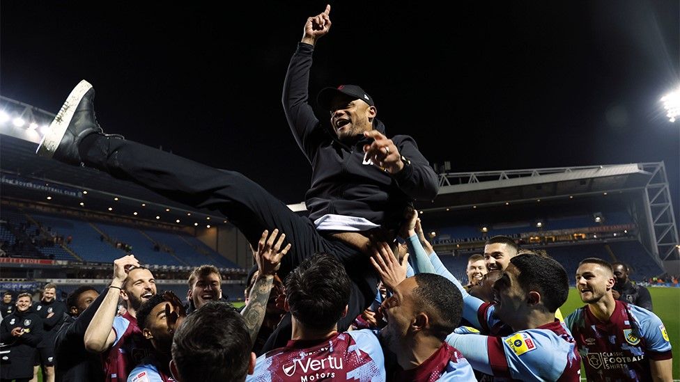 Burnley players lift manager Vincent Kompany after sealing the Championship title