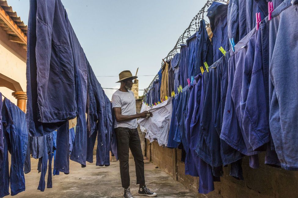 Amah Ayivi inspects rows of blue worker jackets.