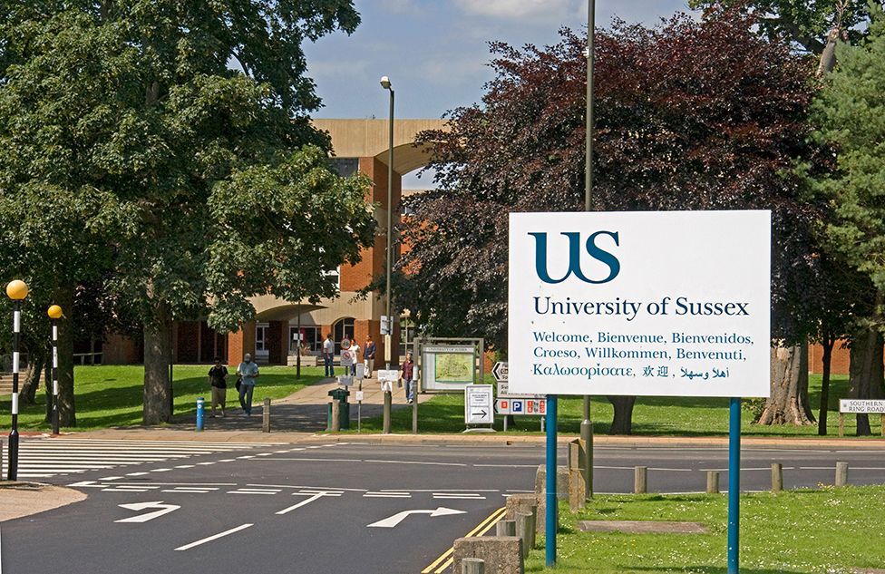 A University of Sussex sign at a crossroads on campus