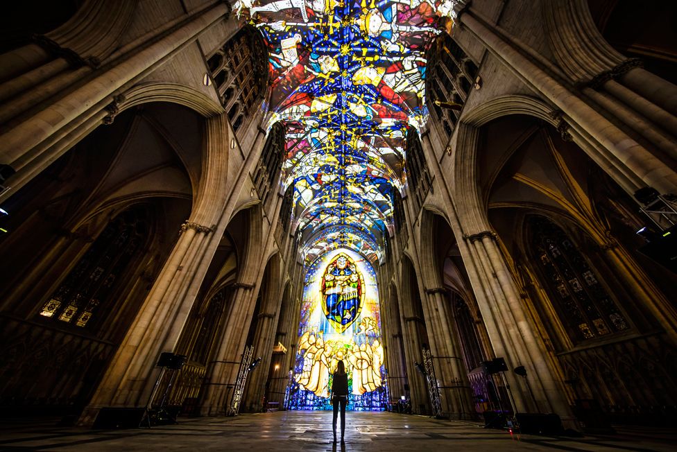 A woman looks at a light projection in a cathedral