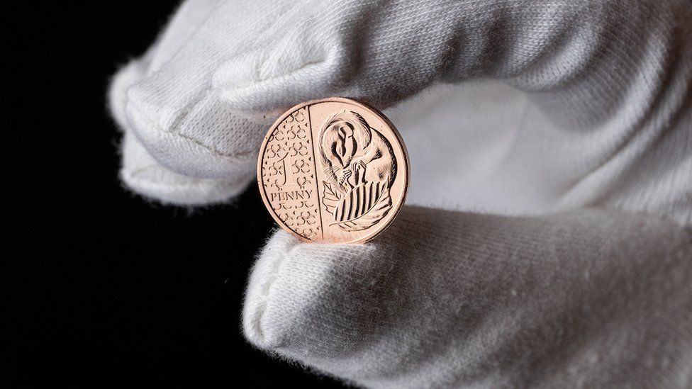 The new 1p coin held in a gloved hand.