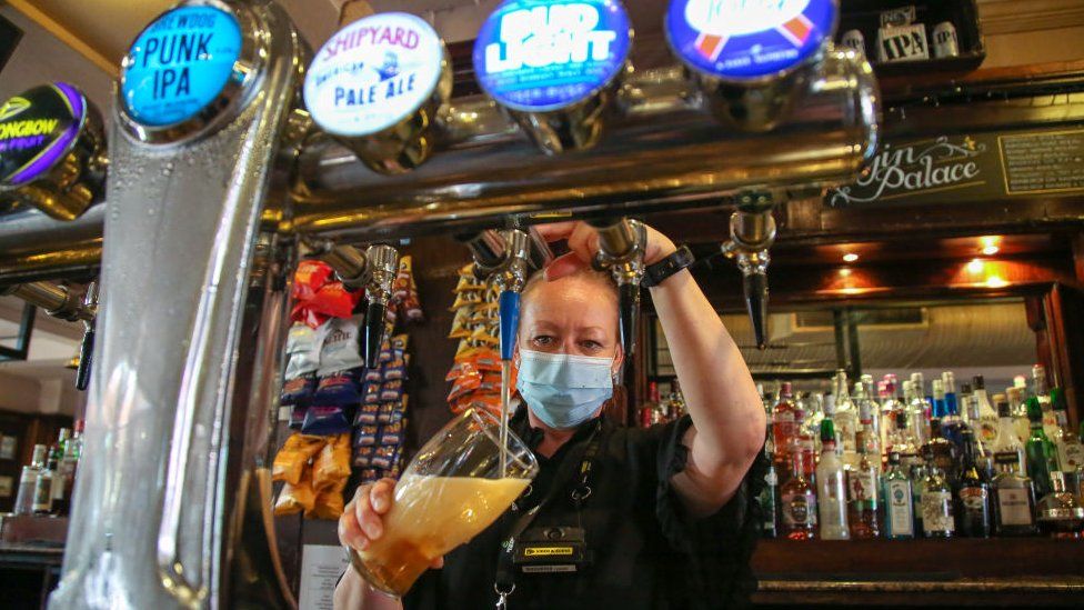 Masked bartender pulling a pint