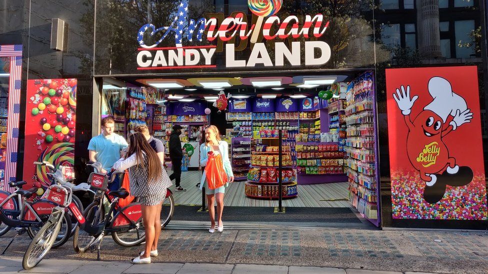 People stand outside an American Candy Land shop on Oxford Street