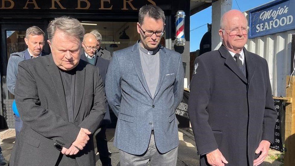 Father Jeffrey Woolnough, left, was among those observing the silence