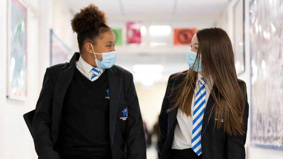 Two girls wearing face masks walk down the corridor of Llanishen High School