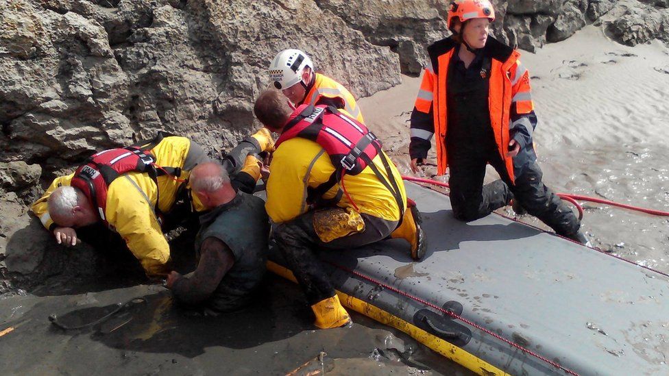 Rescuers struggle to free the man from the quicksand