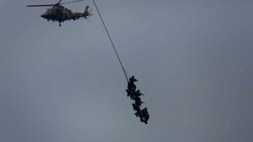 South African special forces soldiers perform an air stunt, hanging from a helicopter with weapons drawn in Durban - Tuesday 21 February 2017