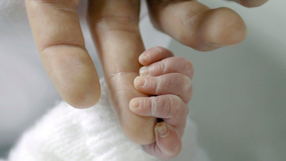 Close up of the hand of a 3 day old baby boy holding his father's finger.