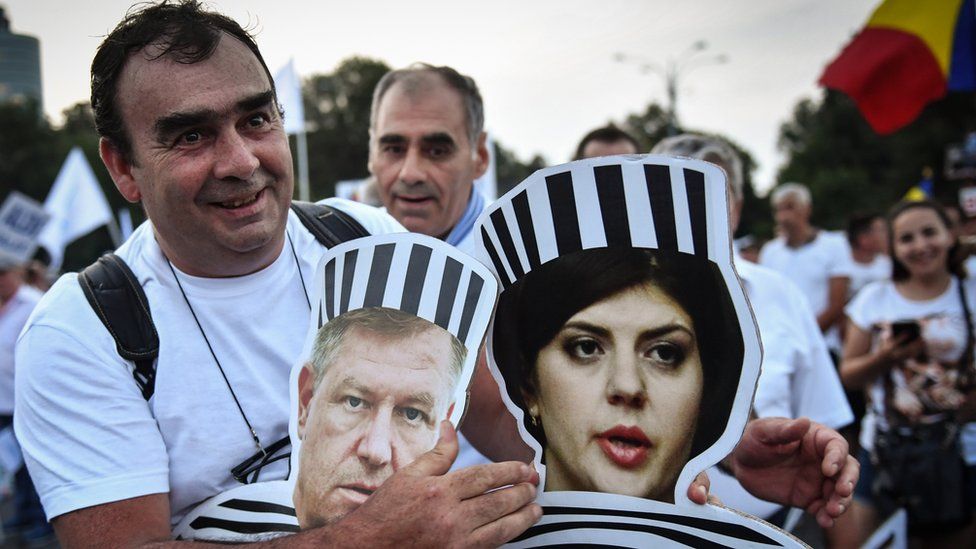 A pro government supporter holds cardboard cutouts showing Romanian President Klaus Iohannis and Chief Prosecutor of the National Anticorruption Directorate Laura Codruta Kovesi in Juna 2018