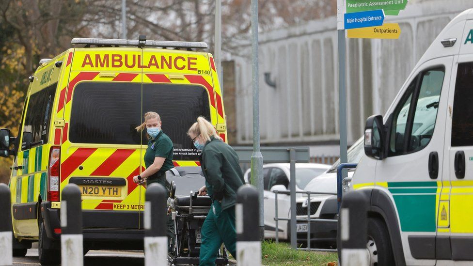 Paramedics handle a trolley at the rear of their ambulance outside Whipps Cross University Hospital in east London on December 13, 2021.