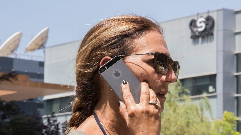 A woman holds a phone outside NSO office