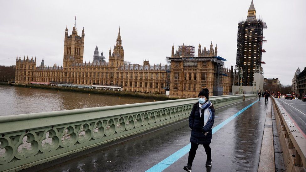 A woman wearing a face mask walks across Westminster Bridge