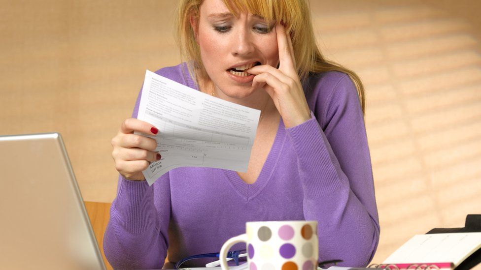 A stock image of a woman looking in horror at a bill